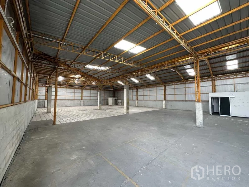 货栈 出租在Mueang Pathum Thani, Pathum Thani - 仓库内部通透，钢结构高屋顶配天窗，混凝土地面并带一处瓷砖区域。