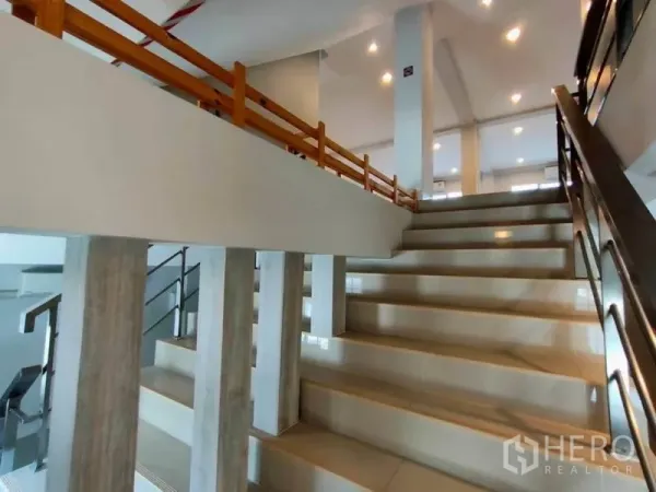 带办公室的家 出租或出售在Bang Na, Bangkok - 室内宽阔楼梯，金属与木质扶手，筒灯照明。