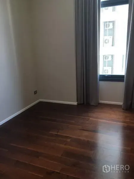 คอนโด ให้เช่าในWatthana, Bangkok - ห้องนอนที่สองโล่ง พื้นไม้สีเข้ม และหน้าต่างสูงพร้อมผ้าม่าน