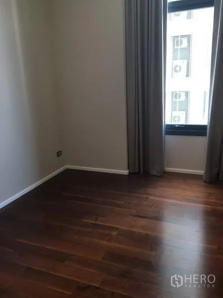คอนโด ให้เช่าในWatthana, Bangkok - ห้องนอนที่สองโล่ง พื้นไม้สีเข้ม และหน้าต่างสูงพร้อมผ้าม่าน
