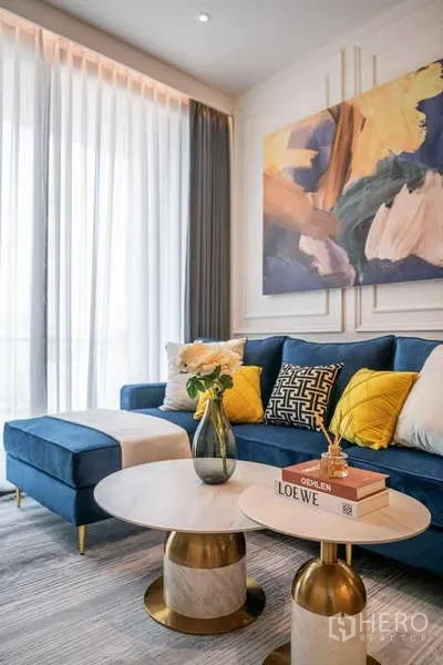 公寓 出租或出售在Watthana, Bangkok - 客厅蓝色转角沙发、双层茶几和抽象画