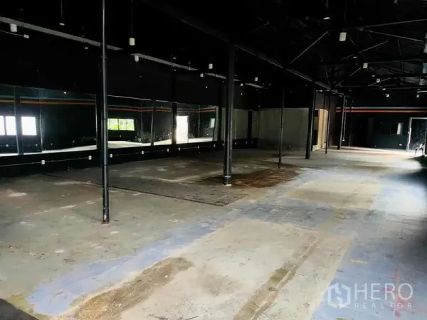Warehouse for rent in Suan Luang, Bangkok - Spacious warehouse interior with high ceiling, steel columns, wall mirrors and concrete floor.