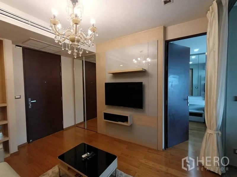 คอนโด ให้เช่าในRatchathewi, Bangkok - พื้นที่นั่งเล่นอบอุ่นด้วยโคมระย้า ทีวีกำแพง และประตูเปิดสู่ห้องนอน