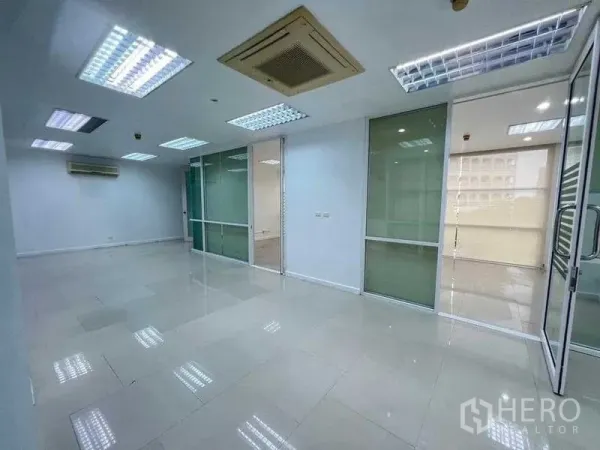 Office Space for rent in Wang Thonglang, Bangkok - Open-plan 100 sqm office with tiled floors, drop-ceiling lights, glass partitions and air conditioning.