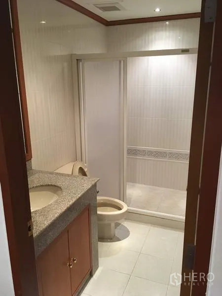 公寓 出租在Sathon, Bangkok - 卫生间带花岗岩洗手台、坐便器与玻璃淋浴间。