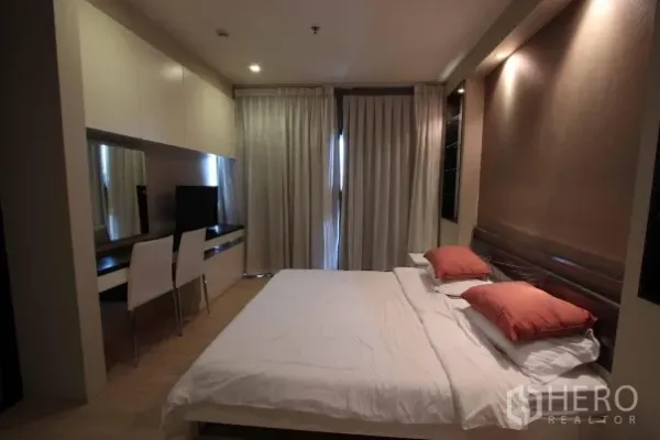 公寓 出租在Khlong Toei, Bangkok - 主卧配大床、整墙书桌与衣柜、电视及遮光窗帘