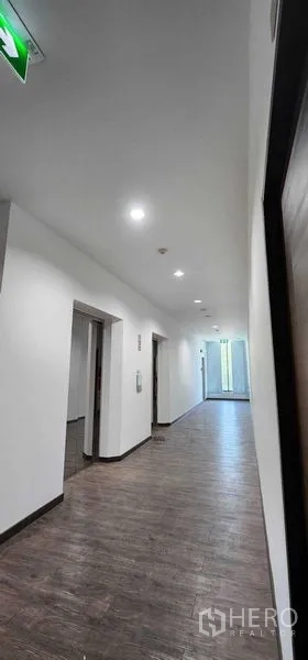 办公空间 出租在Khlong San, Bangkok - 电梯前厅走廊，木地板与筒灯，尽头有自然采光。