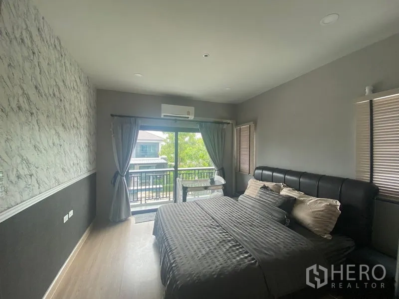 Detached House for rent in Bang Phli, Samut Prakan - Master bedroom with balcony access, large windows, air conditioning and neutral décor.