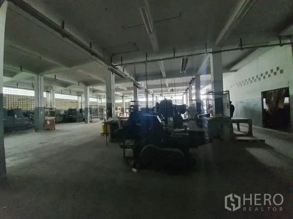 工厂 出售在Bang Khun Thian, Bangkok - 光线较暗的厂区，吊挂电轨与成排重型机器