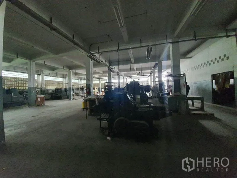 工厂 出售在Bang Khun Thian, Bangkok - 光线较暗的厂区，吊挂电轨与成排重型机器