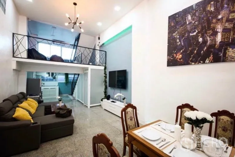 Townhouse for rent in Ratchathewi, Bangkok - Open-plan living and dining area with double-height ceiling, chandelier and loft.