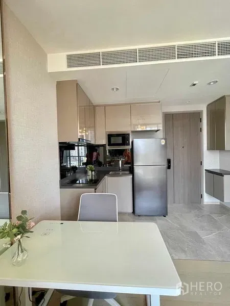 公寓 出租在Ratchathewi, Bangkok - 紧凑现代厨房，亮面柜体、微波炉、冰箱与书桌。