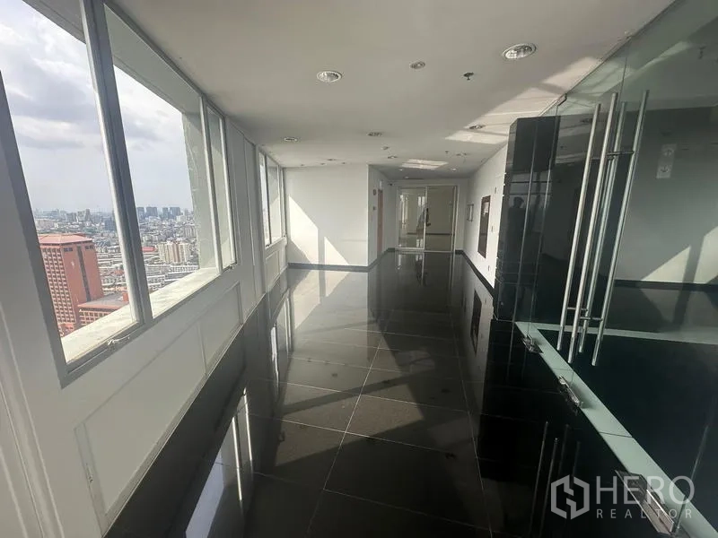 สำนักงาน ให้เช่า - โถงทางเดินชั้นสูง พื้นกระเบื้องดำเงา ทางเข้าแบบกระจก และหน้าต่างต่อเนื่องมองเห็นเมือง