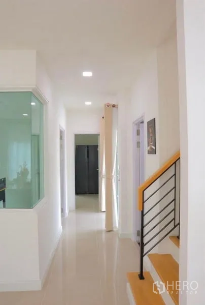 Detached House for rent in Bang Phli, Samut Prakan - Hallway with staircase and glass-walled corner leading to kitchen.
