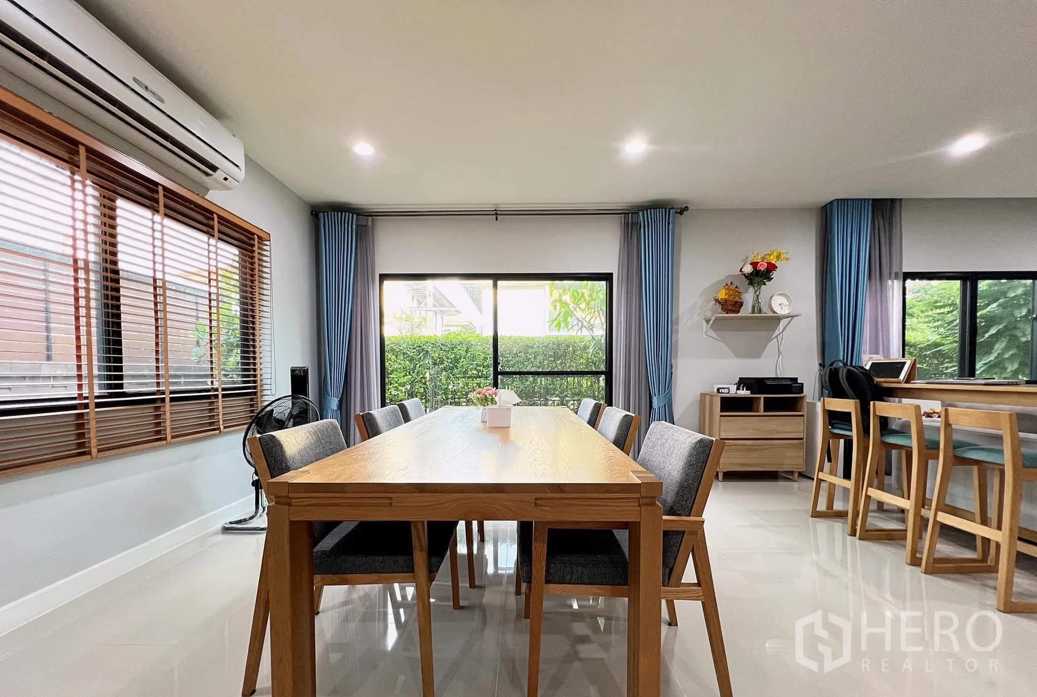 บ้าน ให้เช่าหรือขายในLam Luk Ka, Pathum Thani - พื้นที่รับประทานอาหาร 8 ที่นั่ง ข้างหน้าต่าง ผ้าม่านสีน้ำเงินและวิวสวน