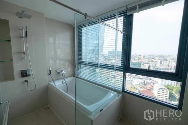 คอนโด ให้เช่าในBang Na, Bangkok - ห้องน้ำสมัยใหม่มีอ่างอาบน้ำติดหน้าต่างบานใหญ่ ฉากกั้นกระจก และฝักบัวเรนชาวเวอร์มองวิวเมือง