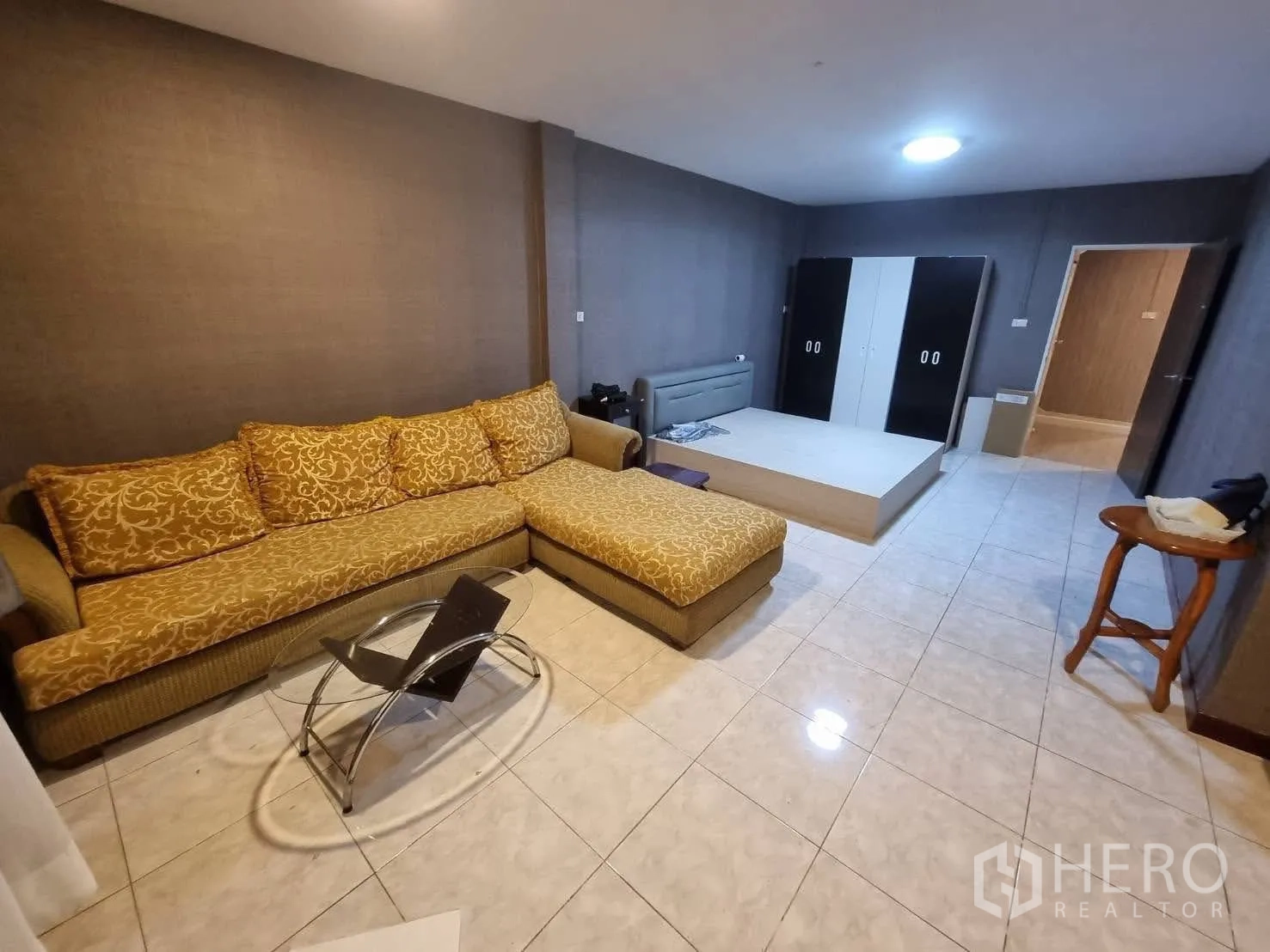Townhouse for rent in Din Daeng, Bangkok - Large multipurpose room with L-shaped sofa, tiled floor and low platform.