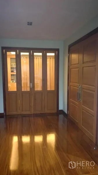 Home Office for sale in Phasi Charoen, Bangkok - Entrance hall with polished wooden floor, paneled doors and a glass room divider.