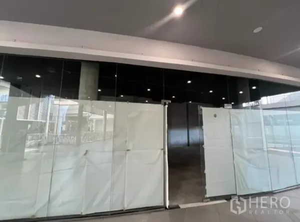 零售空间 出租 - 店铺正面视角，落地玻璃大门与黑色立面，位于购物中心内。