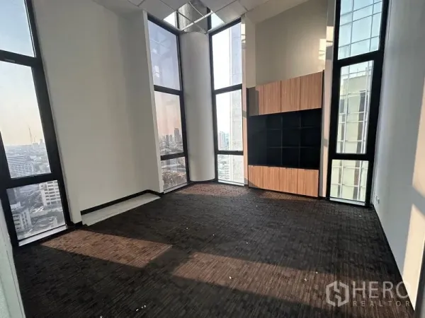 สำนักงาน ให้เช่า - ห้องมุมปูพรม เพดานสูงมาก หน้าต่างกระจกเต็มความสูง พร้อมชั้นไม้บิวท์อินและวิวเมือง