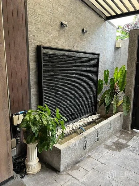 Townhouse for rent in Phaya Thai, Bangkok - Courtyard wall water feature with white pebbles and tropical plants.