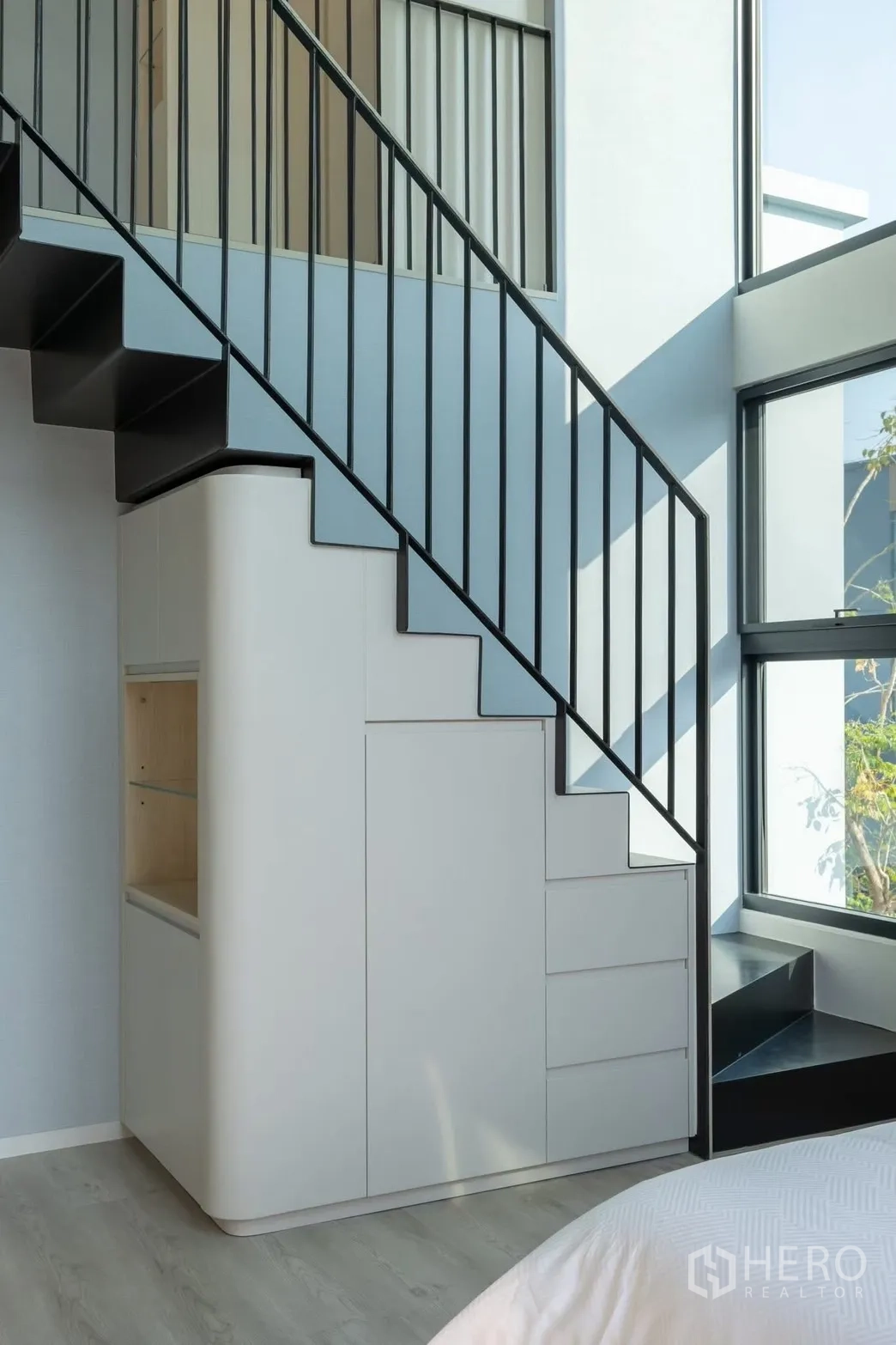 Detached House for rent in Saphan Sung, Bangkok - Staircase detail with black metal balustrade and storage cabinets beneath.