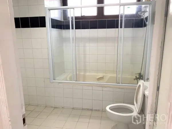 公寓 出租 - 白色瓷砖卫生间，玻璃推拉门浴缸与坐便器。