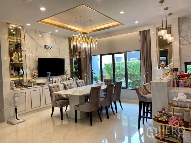 Detached House for rent or sale in Prawet, Bangkok - Elegant dining room with marble feature wall, statement chandelier, and garden views.