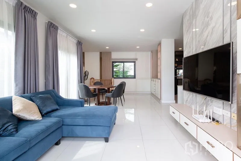 独立式住宅 出租在Bang Phli, Samut Prakan - 开放式客餐厅，蓝色转角沙发、电视墙与嵌灯。