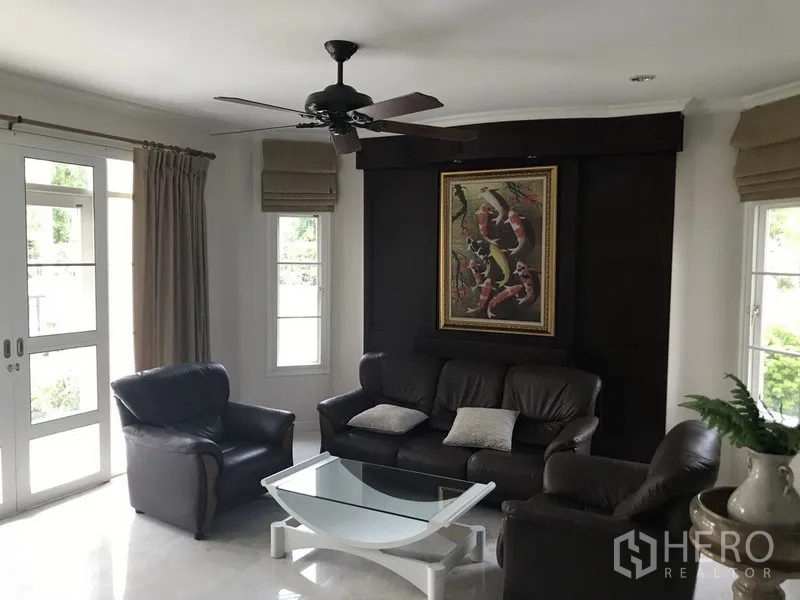 独立式住宅 出租在Phra Khanong, Bangkok - 客厅配皮沙发、吊扇与推拉门，采光充足通向花园。