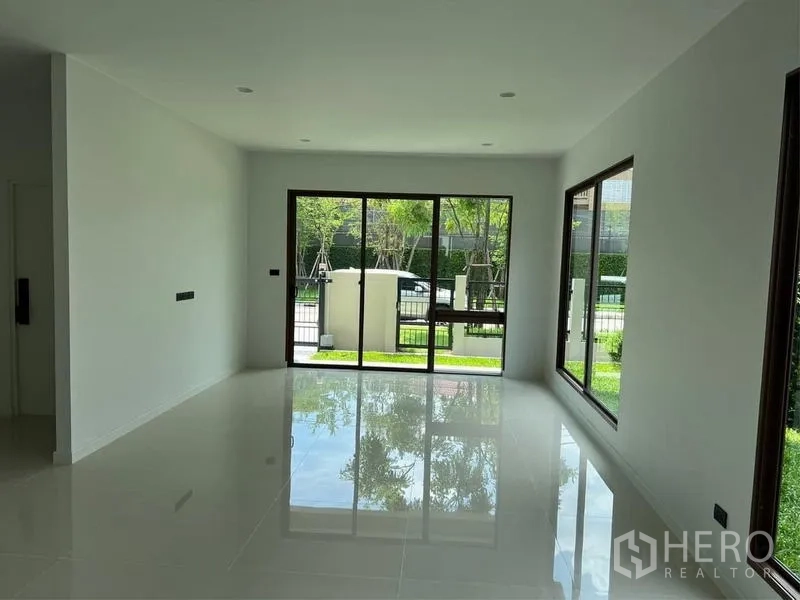 บ้าน ขายในBang Kapi, Bangkok - ห้องนั่งเล่นพื้นกระเบื้องเงา ประตูกระจกบานเลื่อนเปิดสู่สวน