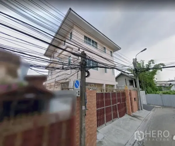 บ้าน ให้เช่าในKhlong Toei, Bangkok - มุมภายนอกตัวบ้านพร้อมประตูรั้วสูง บนถนนย่านที่พักอาศัยเงียบสงบ