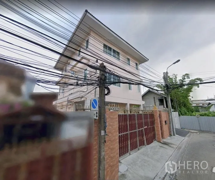 บ้าน ให้เช่าในKhlong Toei, Bangkok - มุมภายนอกตัวบ้านพร้อมประตูรั้วสูง บนถนนย่านที่พักอาศัยเงียบสงบ