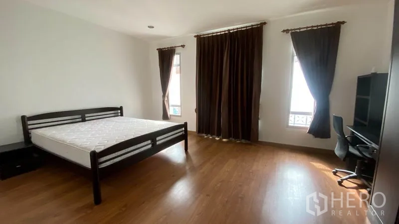 Townhouse for rent in Wang Thonglang, Bangkok - Large master bedroom with bed, desk, big wardrobe, and blackout curtains.
