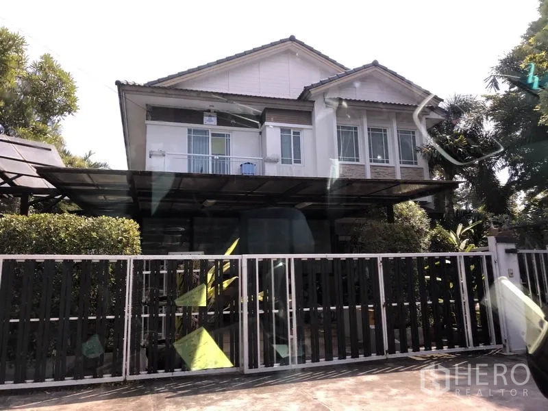Detached House for sale in Bang Kapi, Bangkok - Two-storey detached house in Bang Kapi with sliding metal gate, covered carport, large windows and shaded front garden.