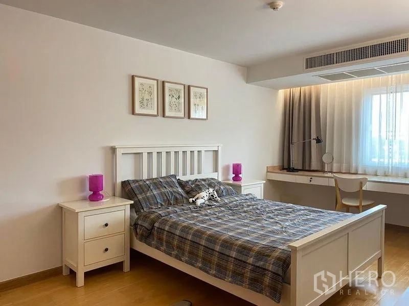 Condominium for sale in Phra Khanong, Bangkok - Spacious bedroom with desk under the window, sheer curtains, and bedside tables.