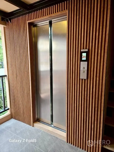 พื้นที่ขายปลีก ให้เช่า - ลิฟต์สแตนเลสในโถงที่ตกแต่งผนังลายไม้เซาะร่อง