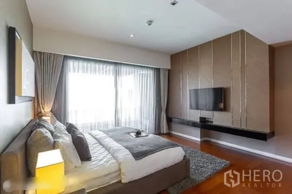 Condominium for rent in Yan Nawa, Bangkok - Primary bedroom with floor‑to‑ceiling windows, sheer curtains, wood floors and a wall‑mounted TV at The Pano condo.