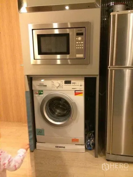 Condominium for rent in Watthana, Bangkok - Built-in stainless microwave above a front-load washing machine beside the fridge.