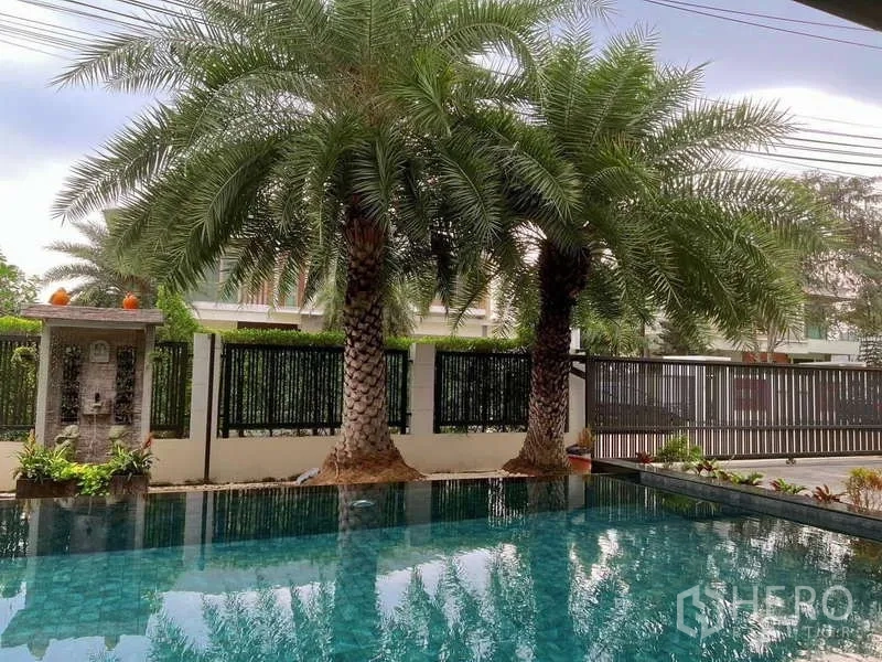 Detached House for rent or sale in Bang Phli, Samut Prakan - Close view of the private pool shaded by tall palms and privacy fence.