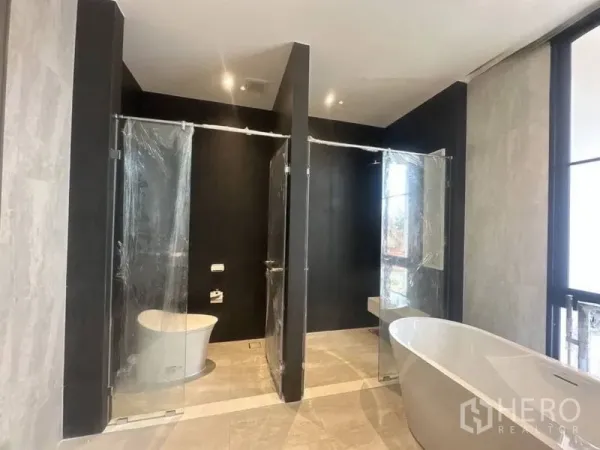 Detached House for rent - Luxury bathroom featuring freestanding bathtub and two glass-enclosed shower stalls with large windows.