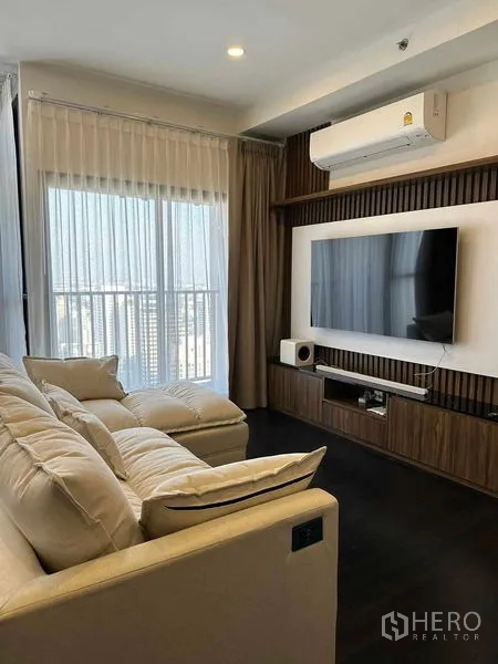 公寓 出租在Khlong Toei, Bangkok - 日光客厅，壁挂电视、空调与阳台旁的纱帘