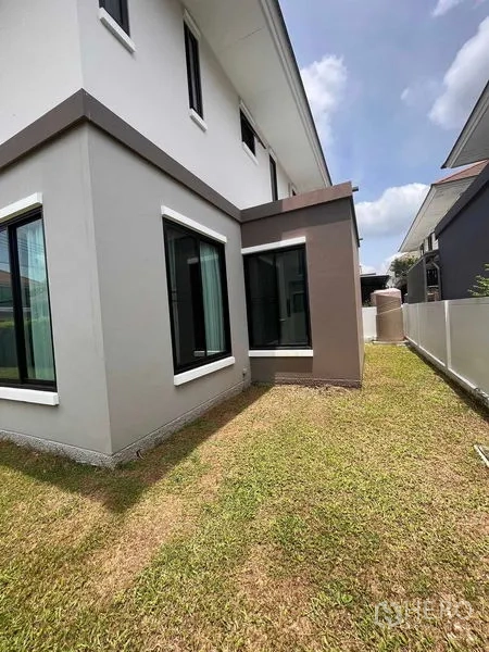 Detached House for rent or sale in Thanyaburi, Pathum Thani - Modern two-storey house exterior showing corner windows and a neatly kept side lawn.