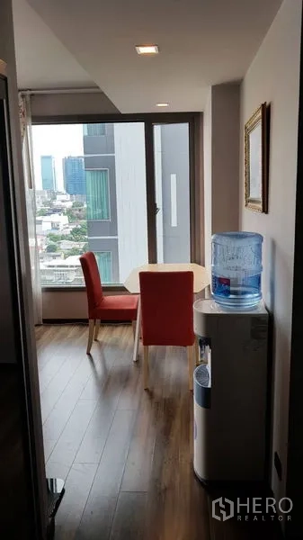 คอนโด ขายในWatthana, Bangkok - มุมรับประทานอาหารริมหน้าต่าง เก้าอี้สีแดง โต๊ะเล็ก พื้นไม้ และเครื่องทำน้ำดื่ม