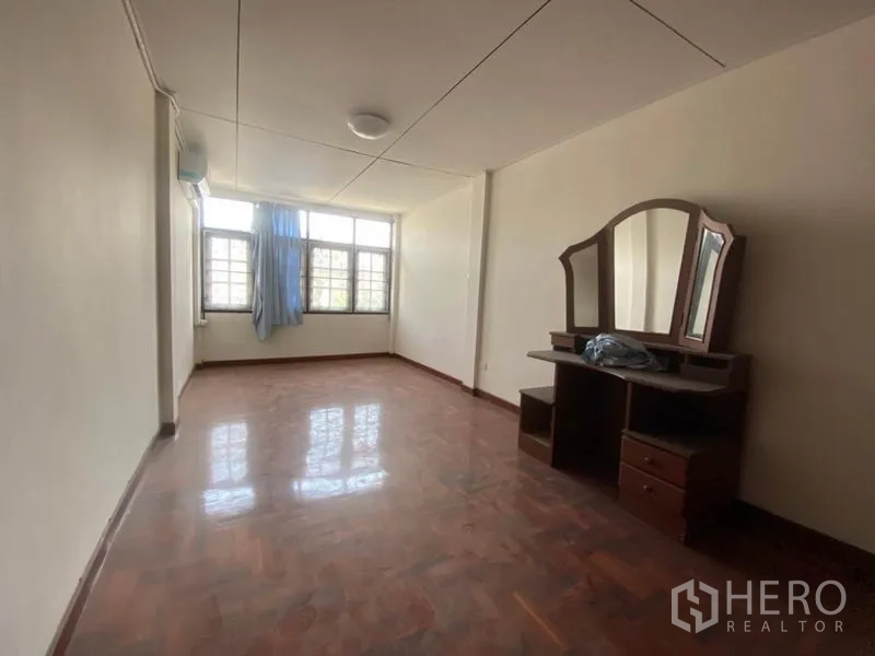 联排别墅 出租在Watthana, Bangkok - 大卧室，宽窗、亮面木地板与木质梳妆台。