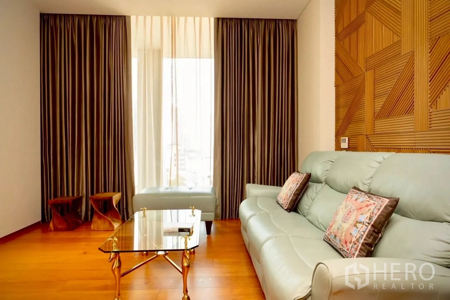 Condominium for sale in Sathon, Bangkok - Sitting room with pale leather sofa, glass coffee table, and geometric wood feature wall.