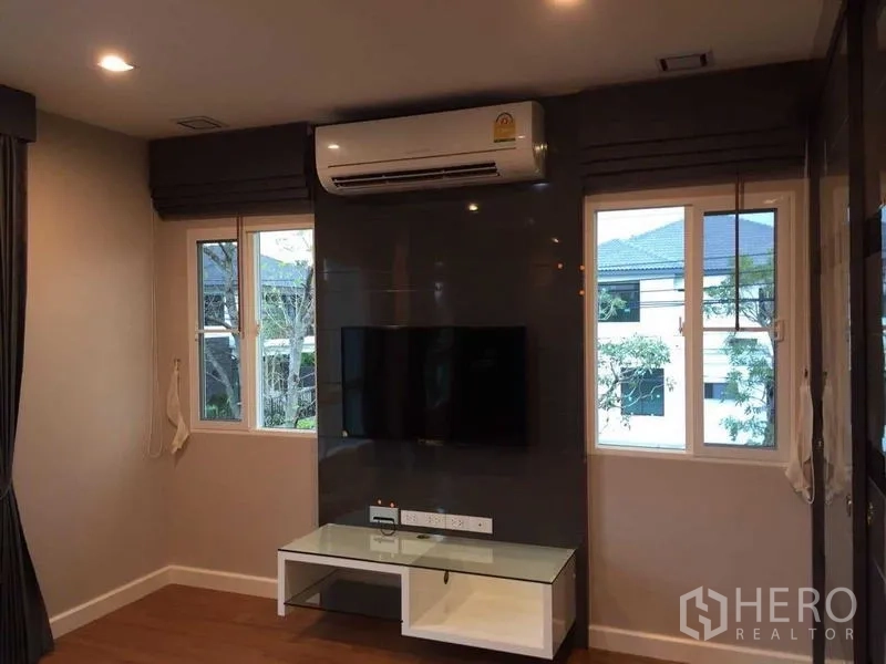 Townhouse for sale in Bang Khae, Bangkok - Cozy room with built-in TV wall, air conditioner and windows on both sides.
