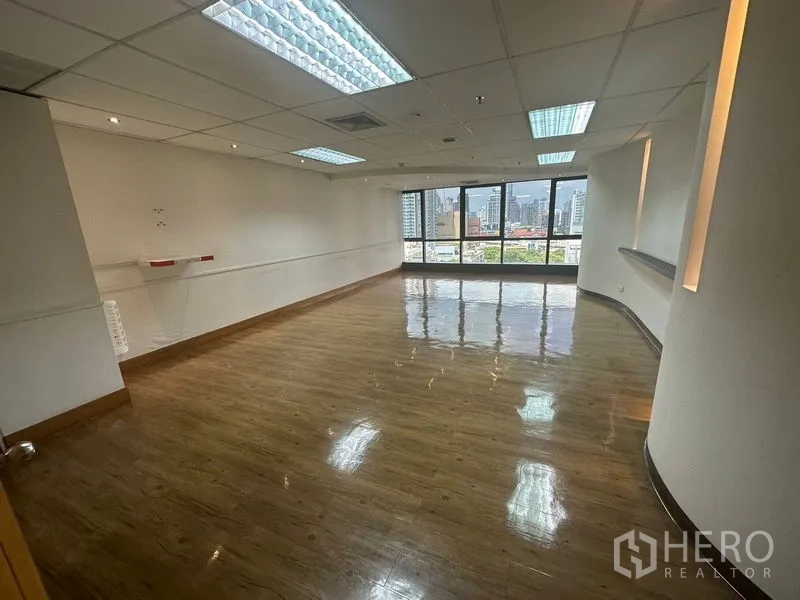 Office Space for rent in Khlong Toei, Bangkok - Large office room with glossy wood flooring, grid ceiling lights, and wide city-view windows.