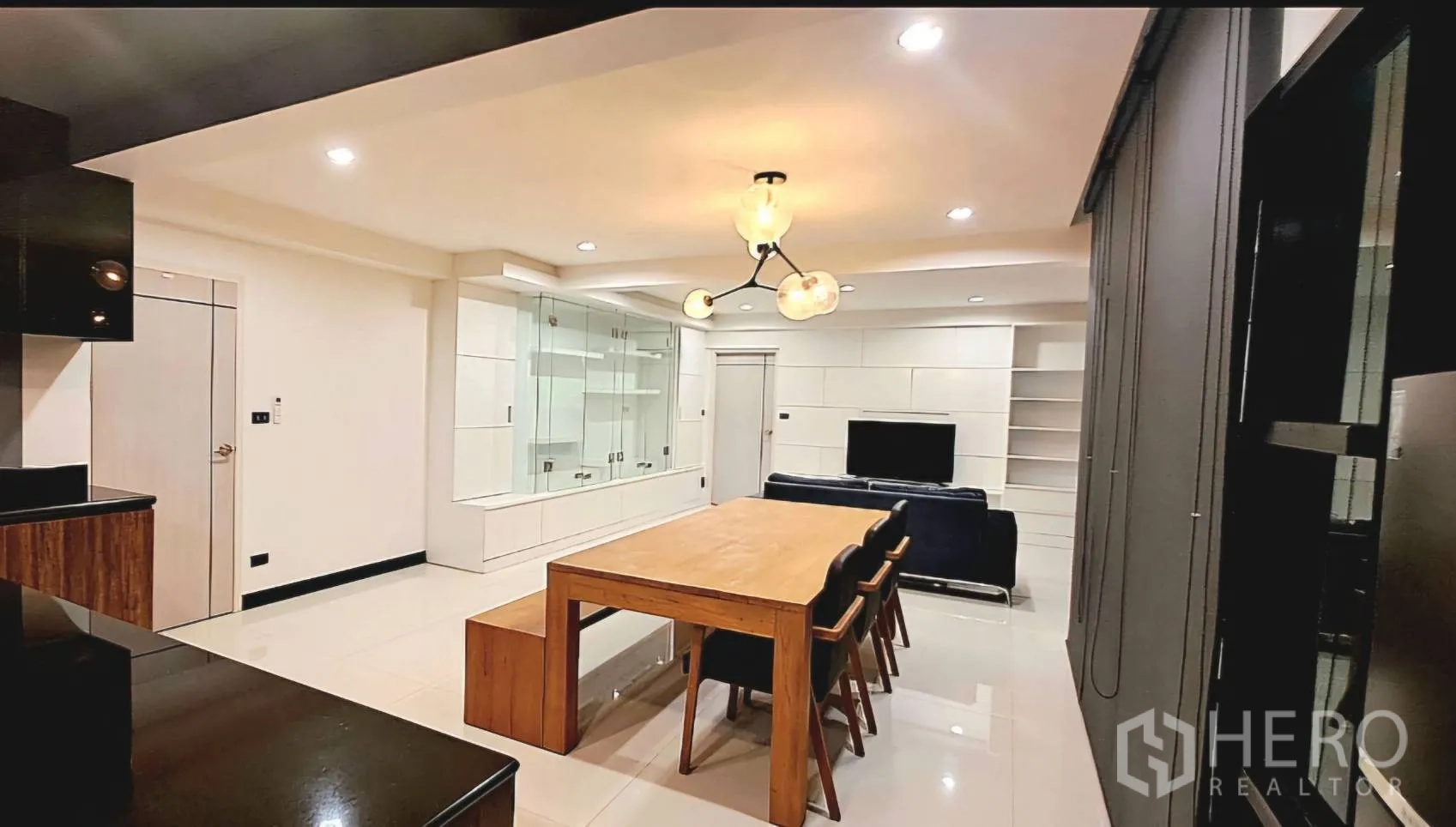 Apartment for rent in Phra Khanong, Bangkok - Living and dining area featuring a chandelier and built-in white shelving.
