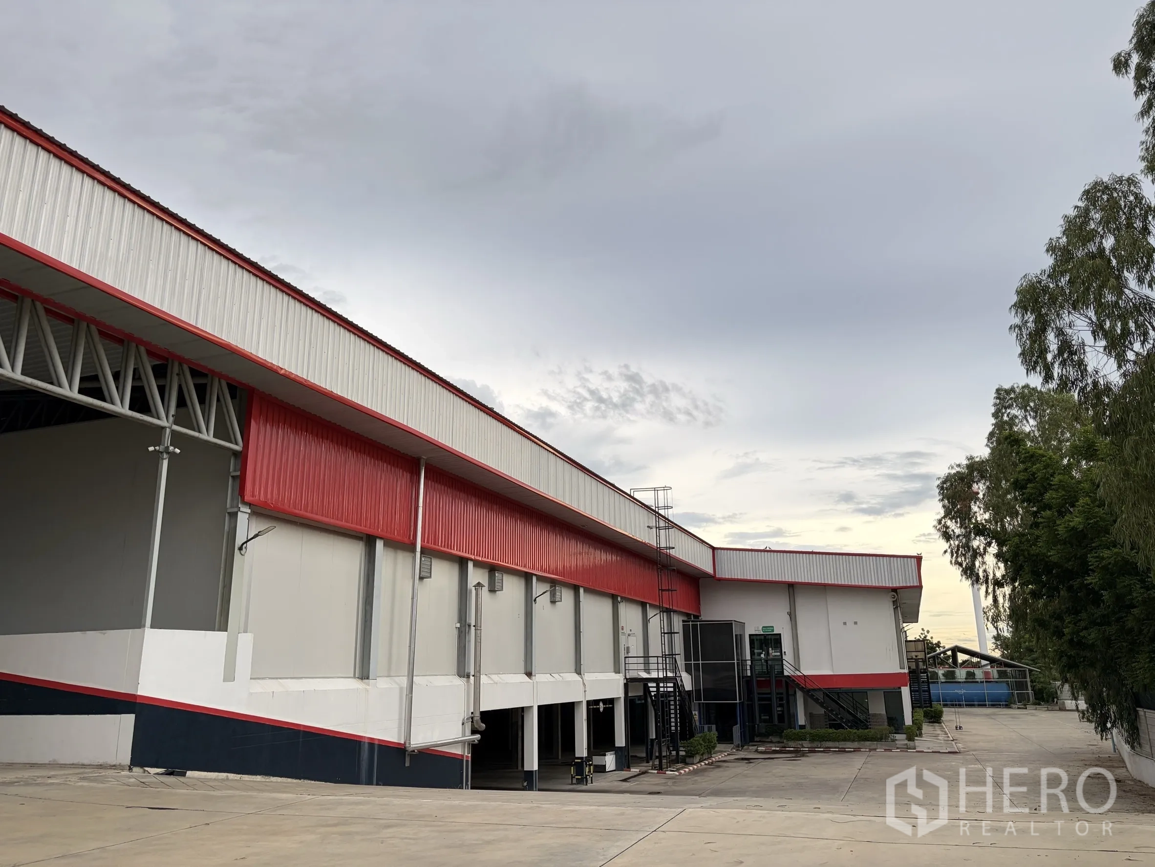Factory for sale in Mueang Nakhon Pathom, Nakhon Pathom - Long exterior elevation of the factory beside spacious driveway.